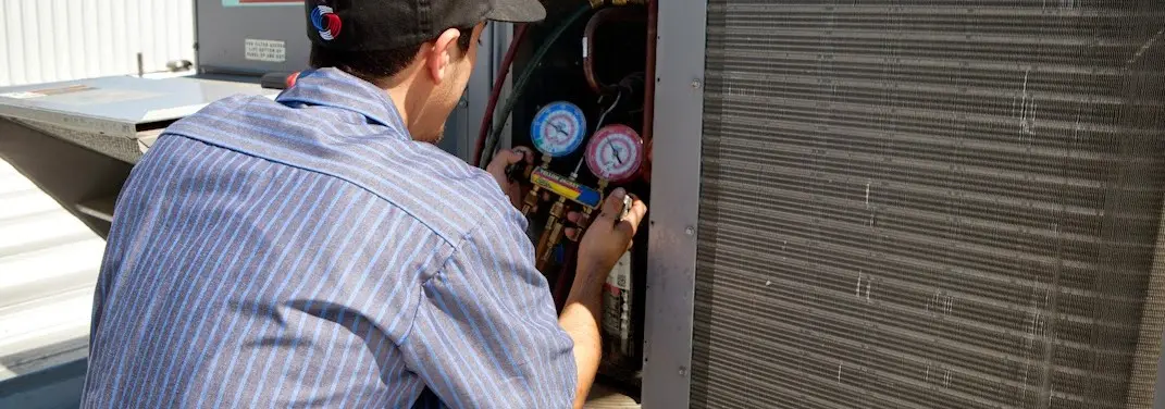 HVAC technician servicing a condenser unit in Plains