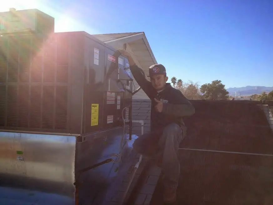 HVAC technician performing Air Duct Cleaning on a rooftop unit in Plains
